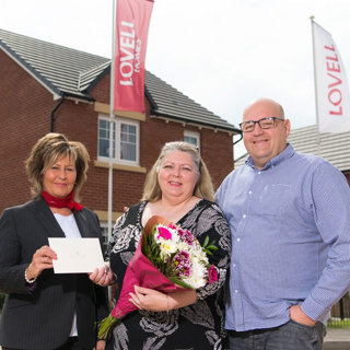 MH 230619 Lovell 1355 Lovell Homes Sales Advisor Sue Presenting Debra And David With Their Celtic Manor Voucher
